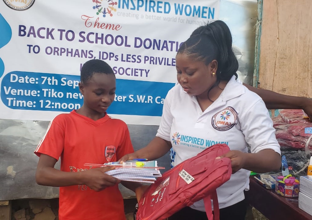 IWO volunteer handing back-to-school supplies to a child